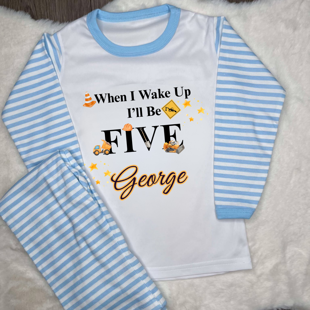 Blue striped pyjamas with text saying when I wake up I’ll be and images of diggers and construction equipment