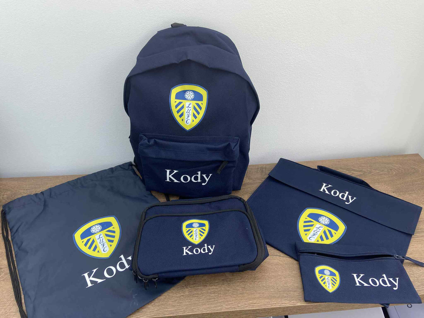 Navy blue bags with 'Kody' branding on a wooden surface