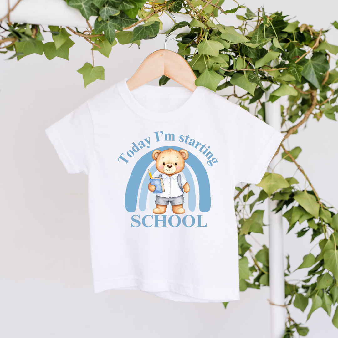 White t-shirt with a bear graphic and text on a hanger against a green leafy background