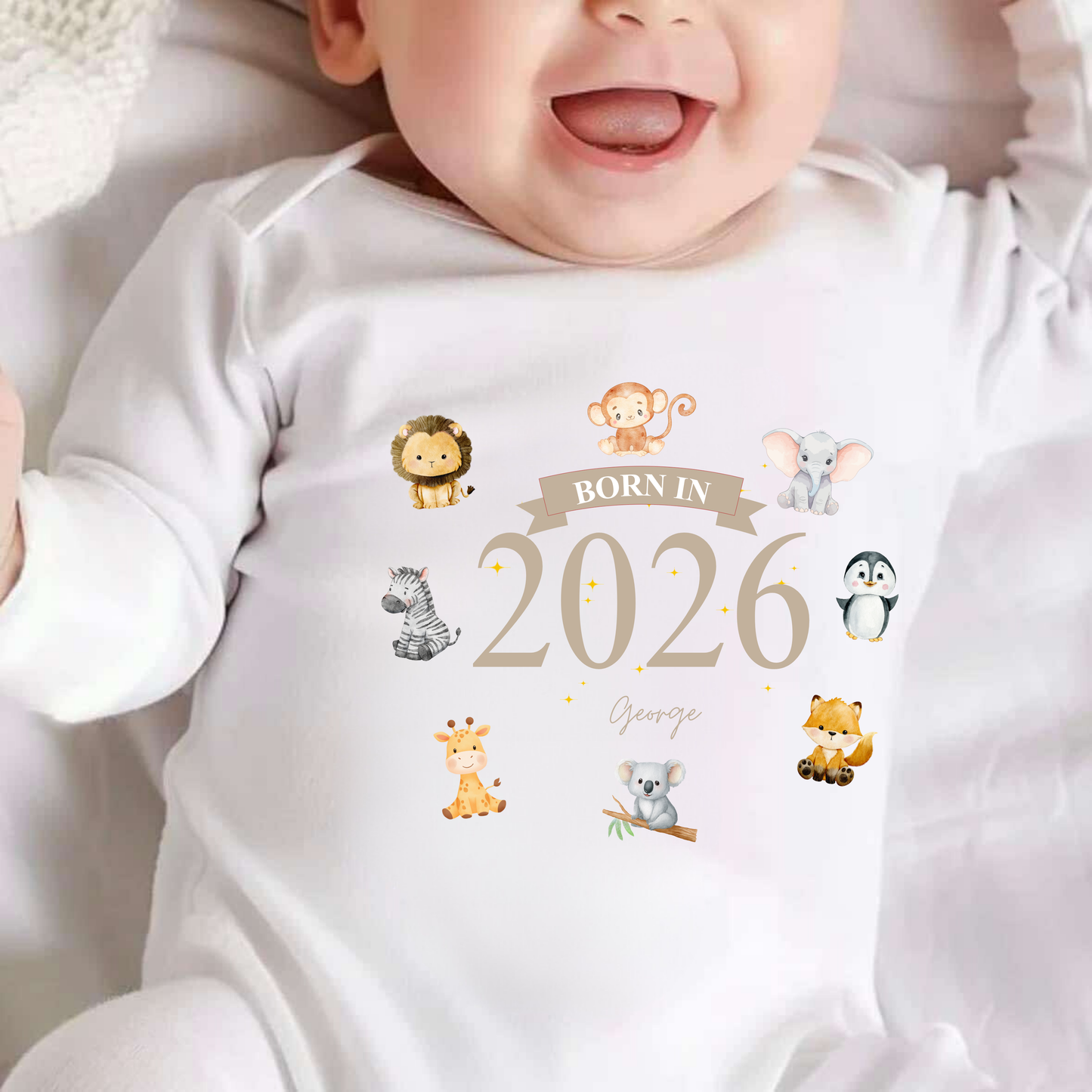 Baby wearing a white onesie with animal illustrations and 'Born in 2026' text.