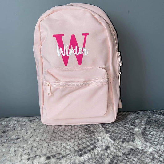 Light pink7 litre backpack with pink and white name and initial.