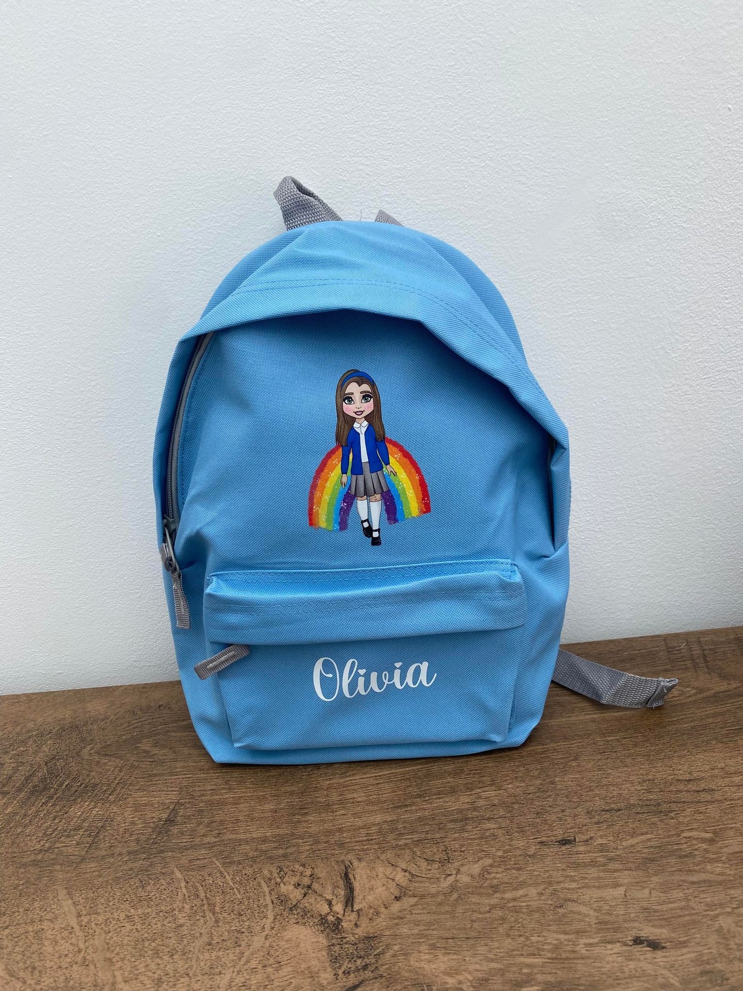 A blue character backpack with a personalized name 'Olivia' printed on the front pocket, featuring a character design with a child's appearance.