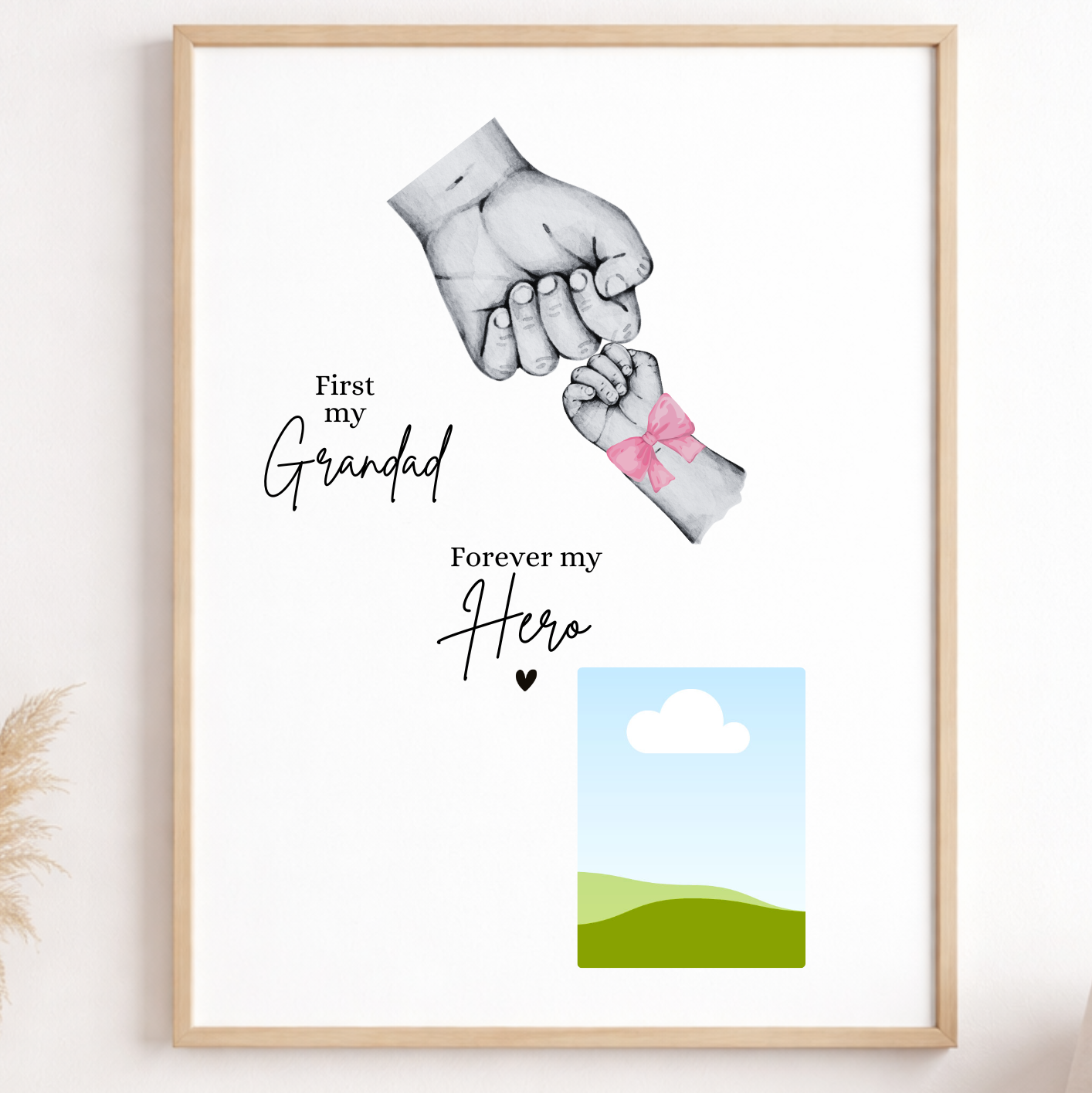 Framed artwork with two hands holding each other, text 'First my Grandad Forever my Hero', and a small landscape illustration on a wall.