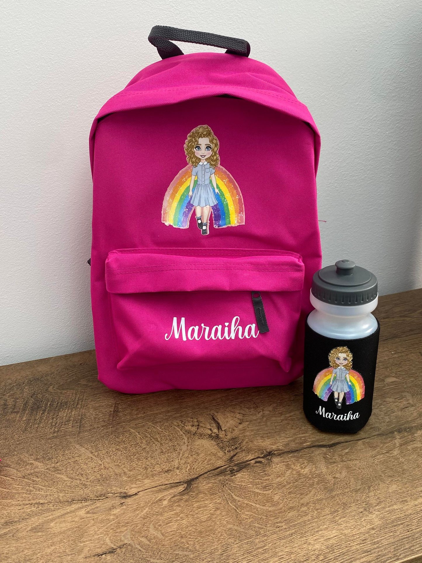 Pink 12 litre personalised backpack with a image of a doll and a rainbow with white text saying: Maraiha