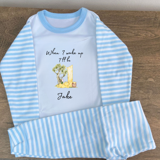 Blue striped pyjamas with the words when i wake up ill be 1 with an image of pooh and piglet wonder a tree eating honey