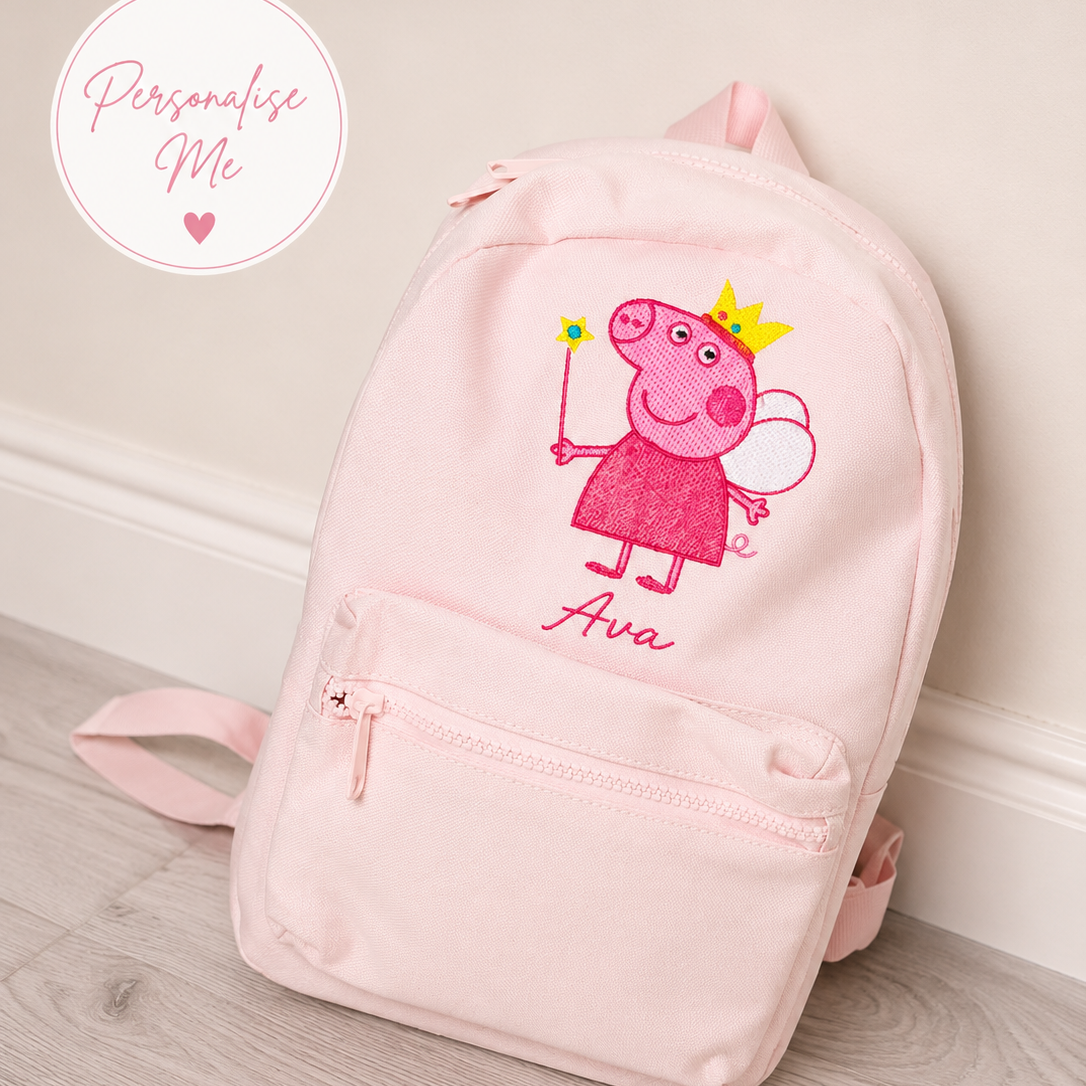 Pink backpack with a fairy-themed design of a character and the name 'Avva' on a wooden floor.