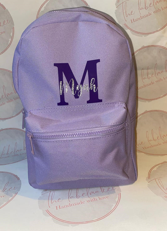 A purple 7 litre backpack with a initial and name in purple and white text.