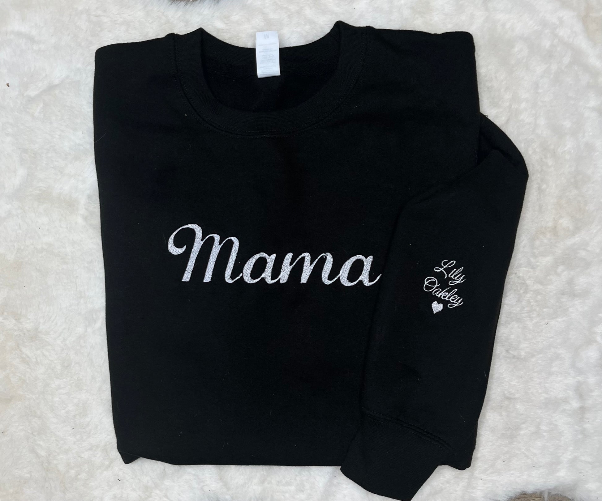 Black sweatshirt with 'Mama' and 'Lily Oakley' text on a textured white background