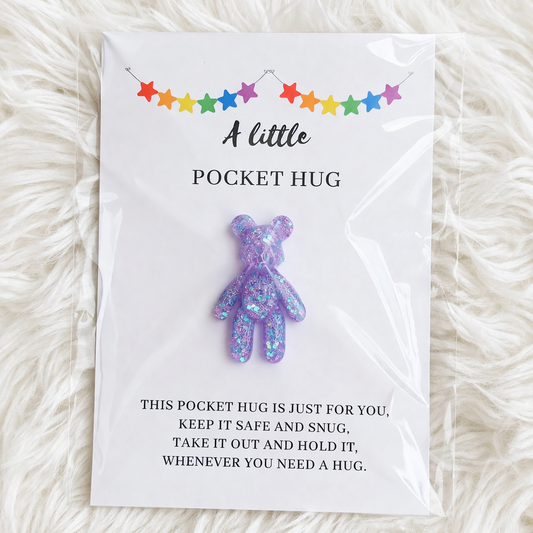 Purple glittery pocket hug toy on a card with text on a white fluffy background