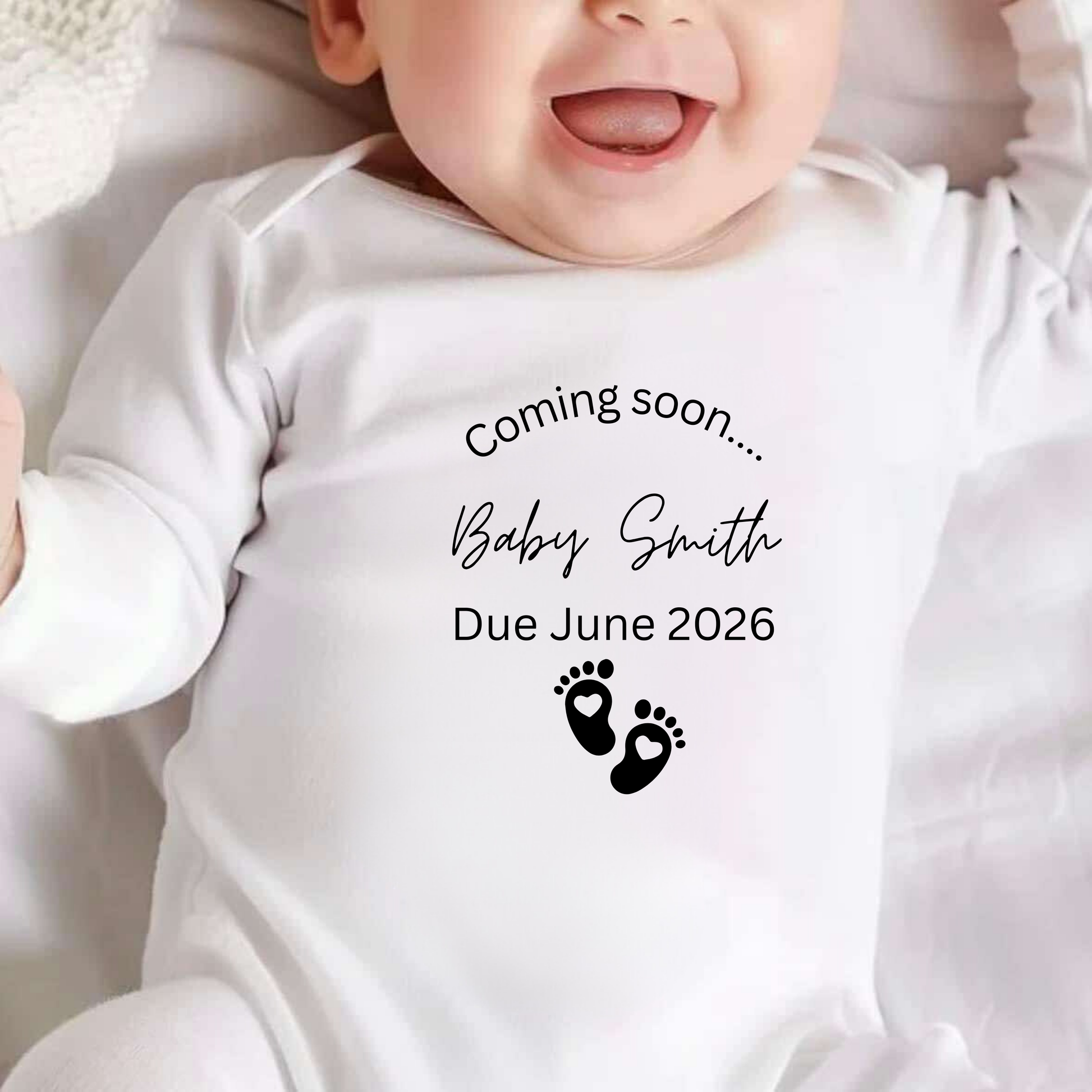 Baby in a white onesie with 'Coming soon... Baby Smith Due June 2026' text and footprints.