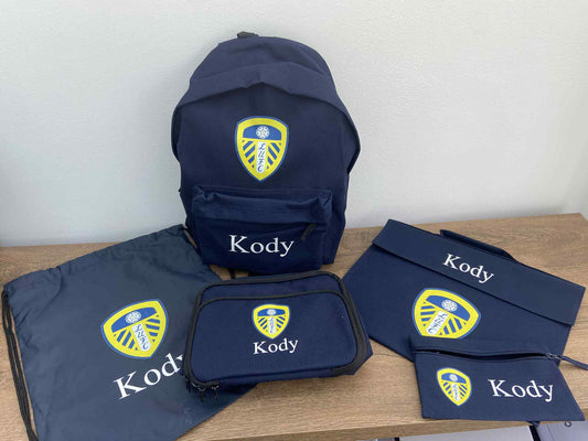 Navy blue bags with 'Kody' branding on a wooden surface