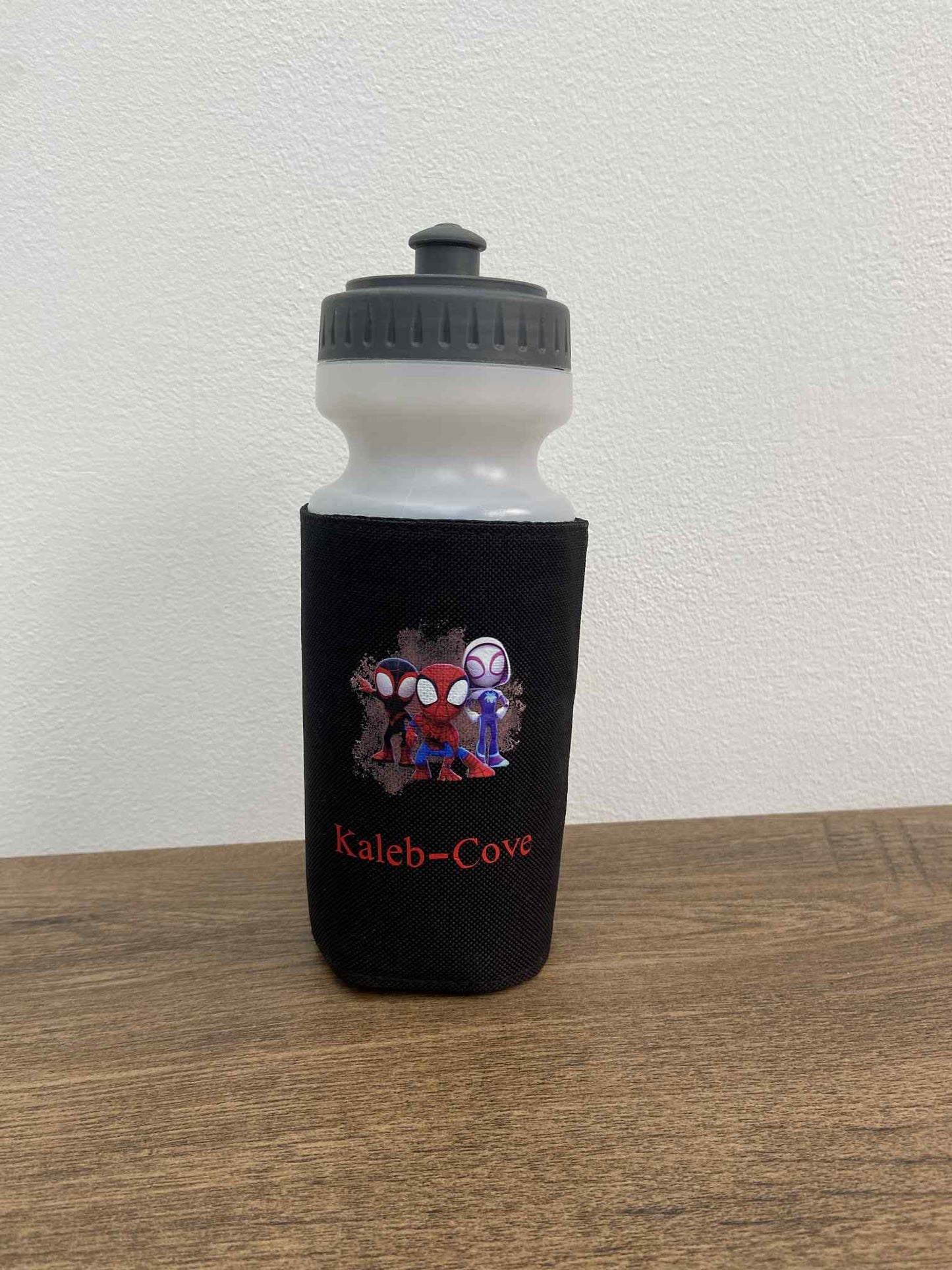 Water bottle with black sleeve featuring cartoon characters on a wooden surface.
