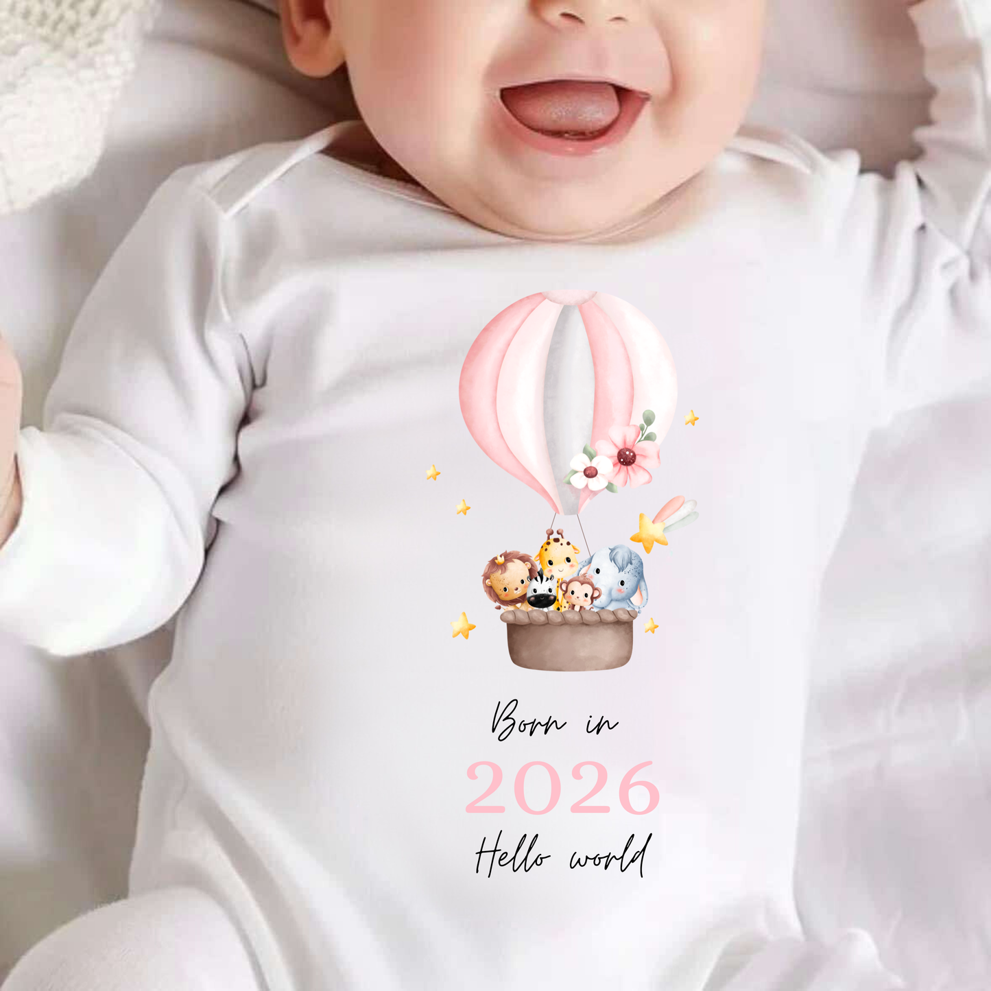 Baby wearing a onesie with a hot air balloon design and text 'Born in 2026 Hello world'.