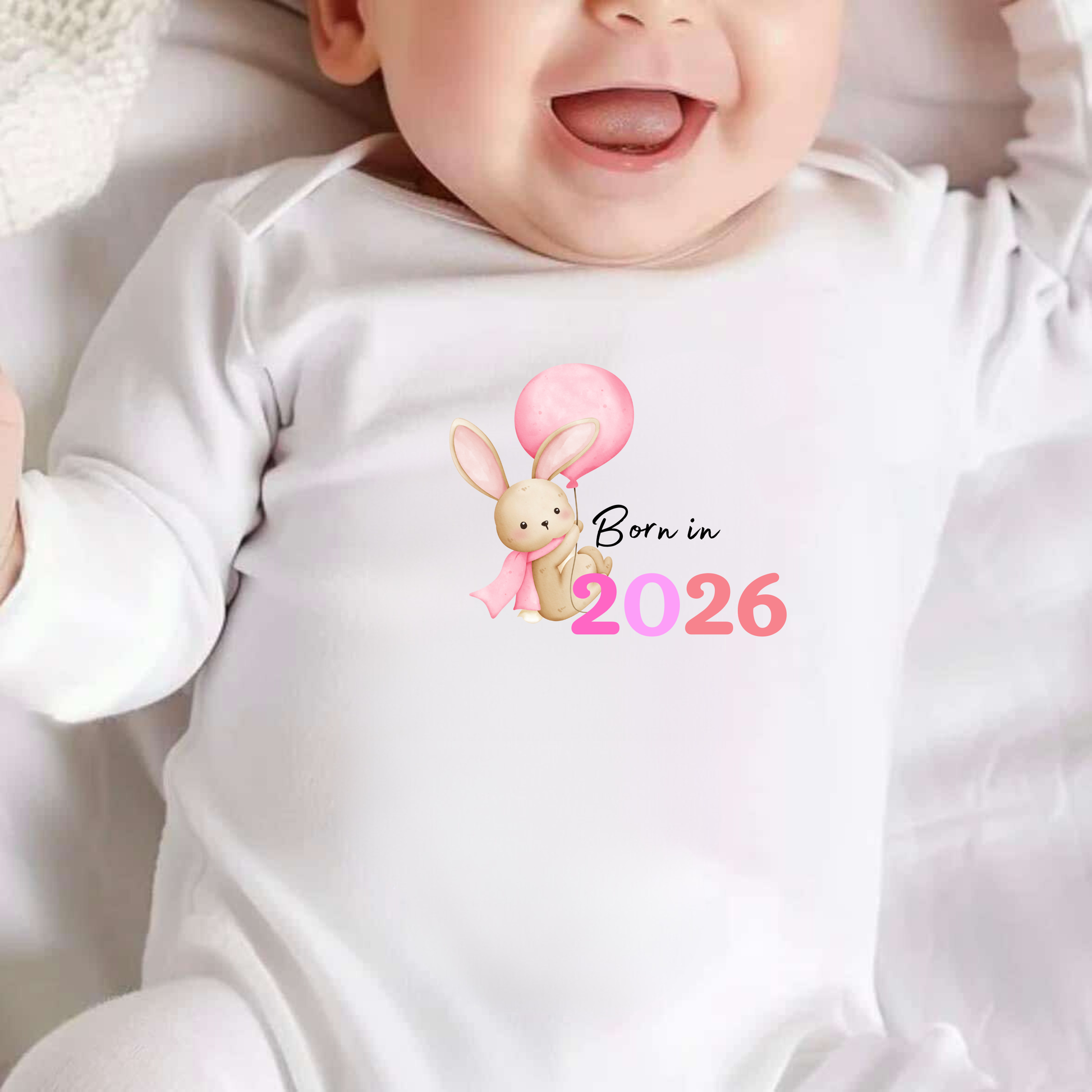 Baby wearing a white onesie with a bunny design and 'Born in 2026' text.