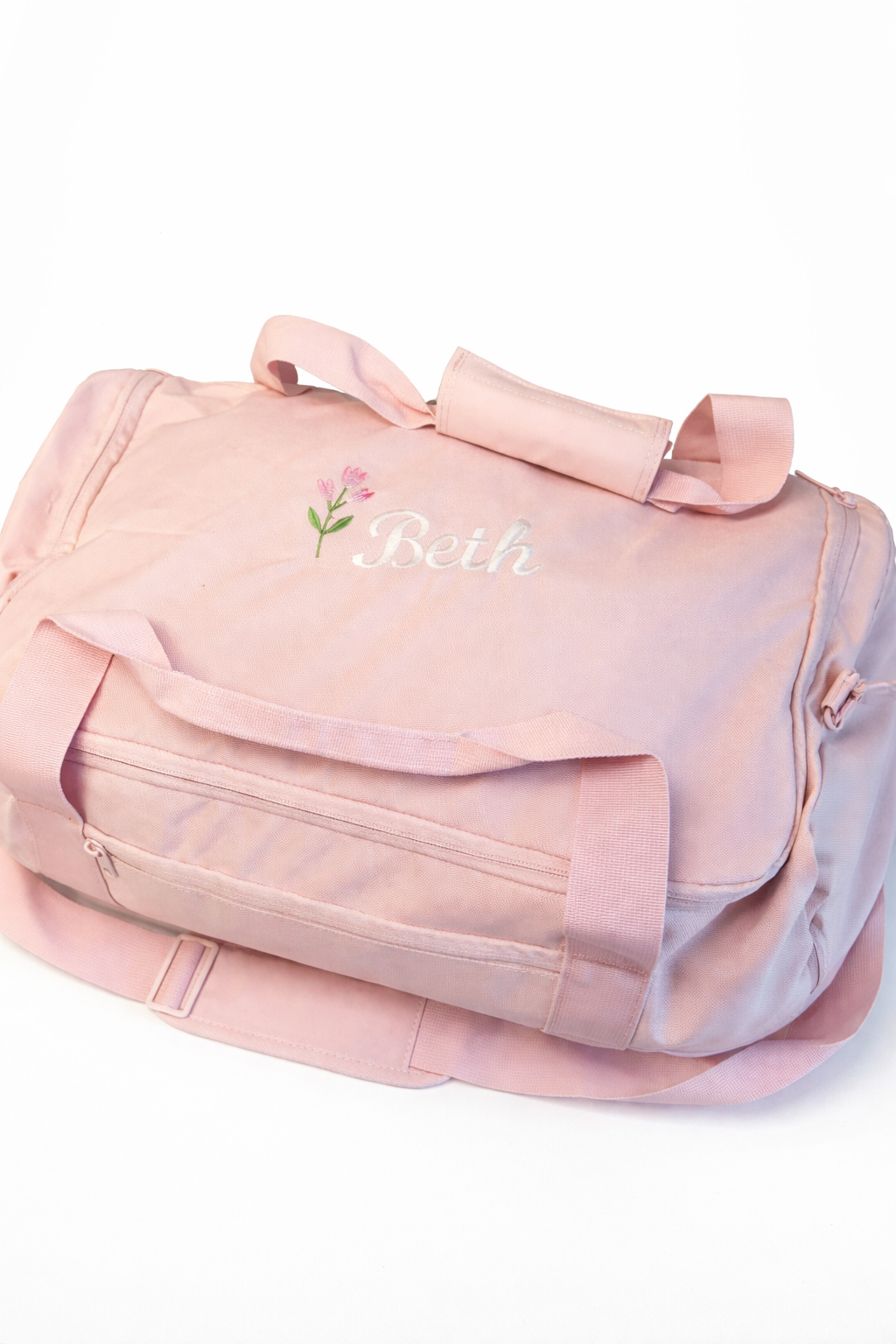 Pink duffel bag with floral design and 'Beth' text on a white background
