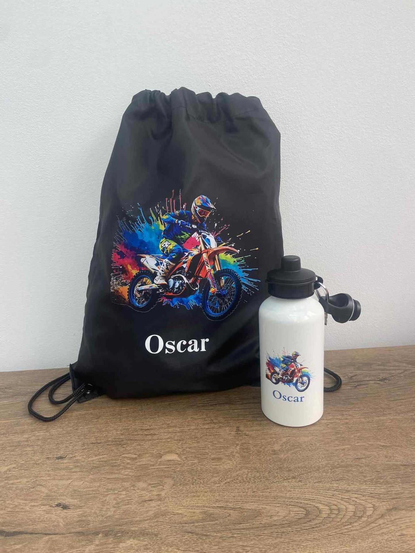 Black drawstring bag and white water bottle with 'Oscar' design on a wooden surface.