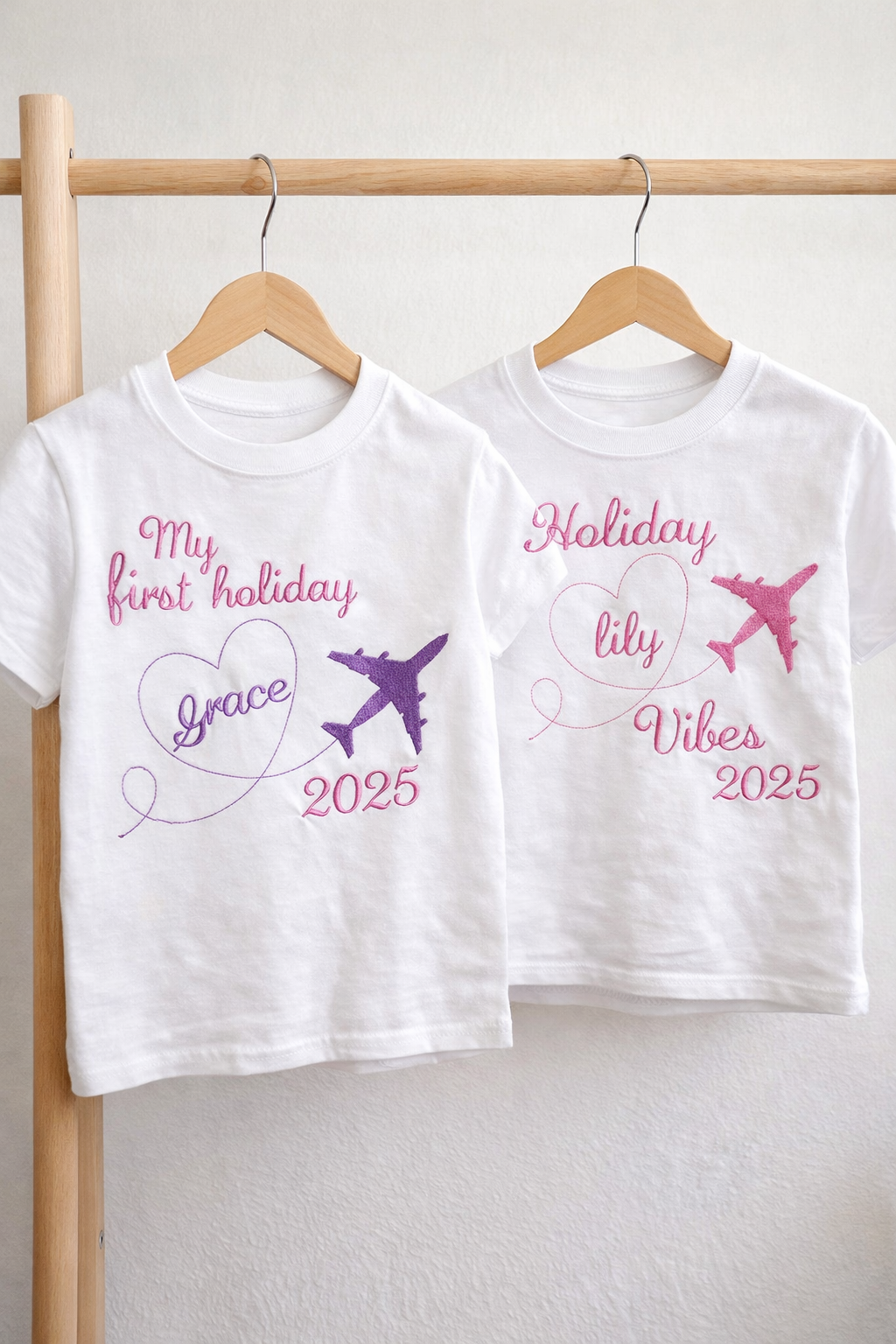 Two white children's t-shirts with personalized text and airplane graphics on a wooden rack.