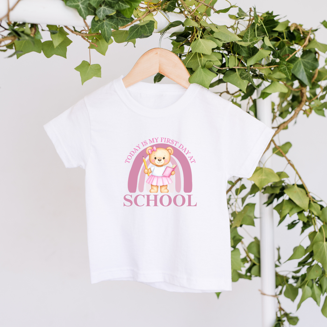 White t-shirt with a bear design and text on a hanger against a green leafy background