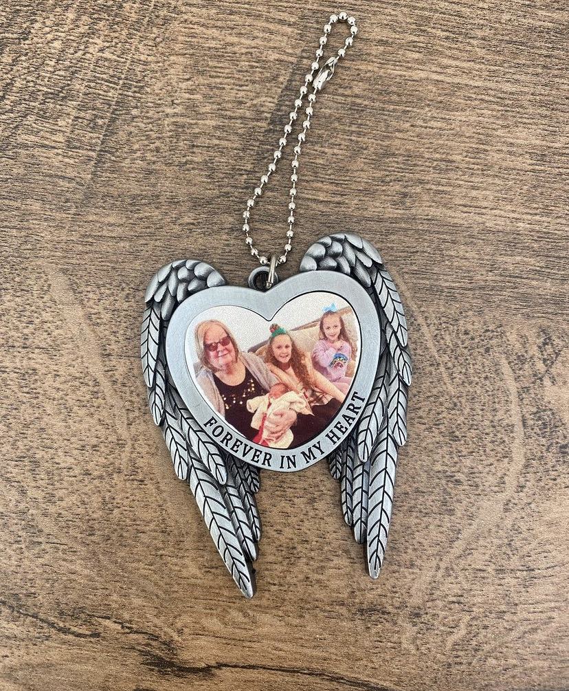 A silver-colored angel wings ornament with a space for a photo and the text 'Forever in my heart', intended for hanging on a tree.
