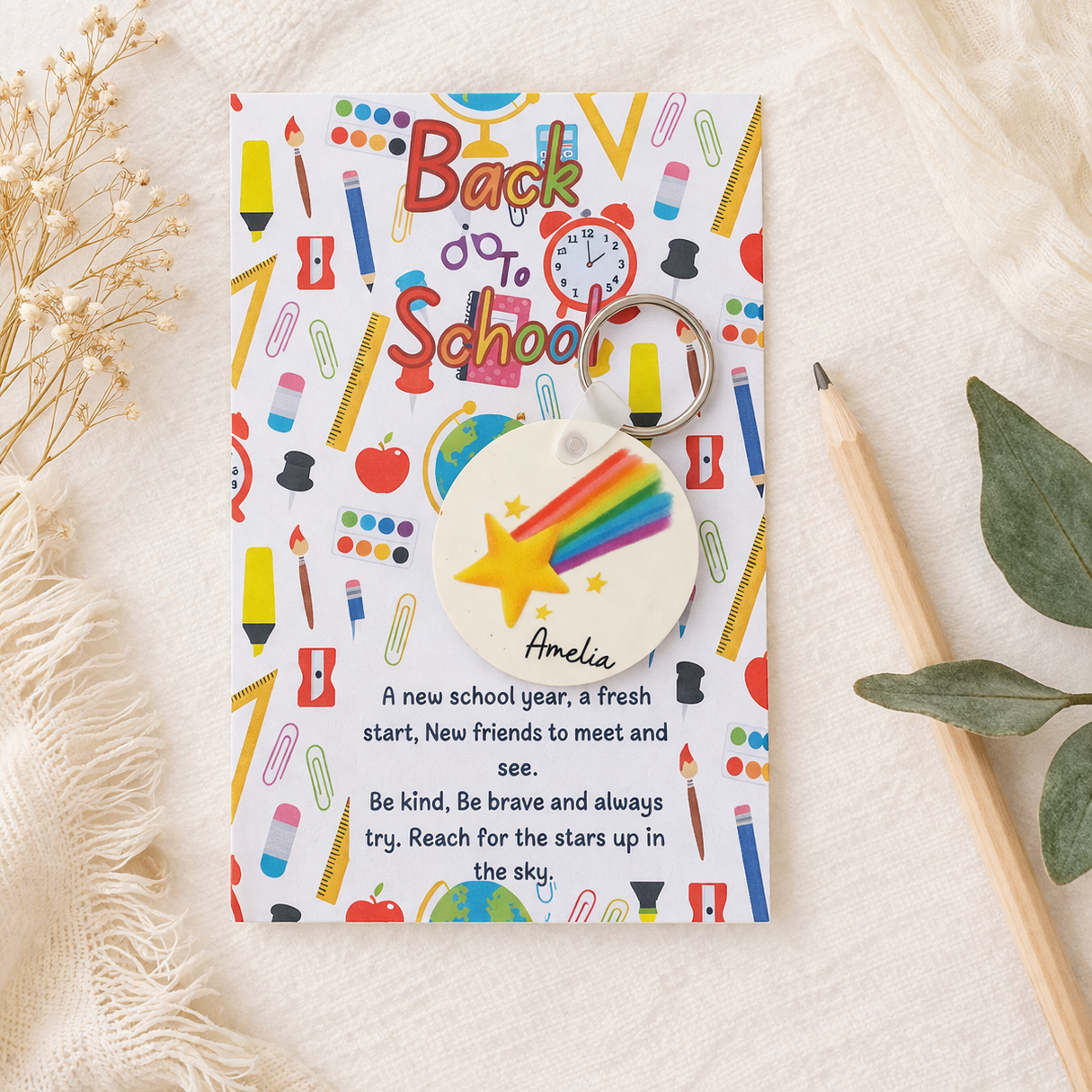 Colorful 'Back to School' themed keychain and card on a textured surface with a pencil and leaves.