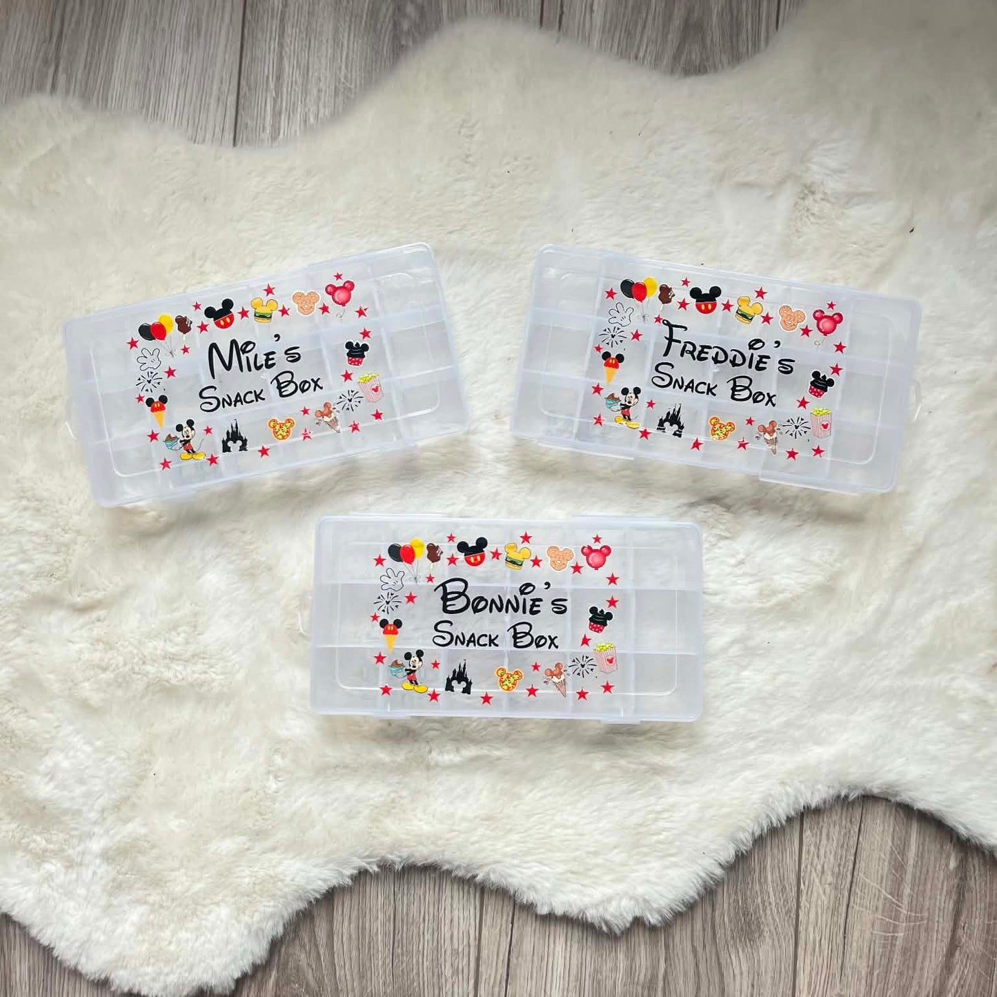 Three personalized snack box labels with cartoon characters on a white fluffy surface.