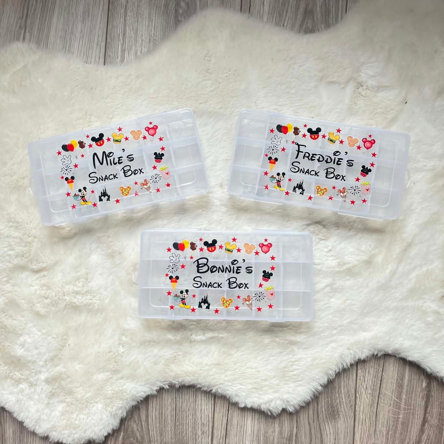 Three personalized snack box labels with cartoon characters on a white fluffy surface.