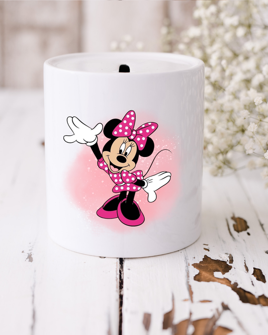 White ceramic money box with Minnie Mouse design on a wooden surface with flowers in the background