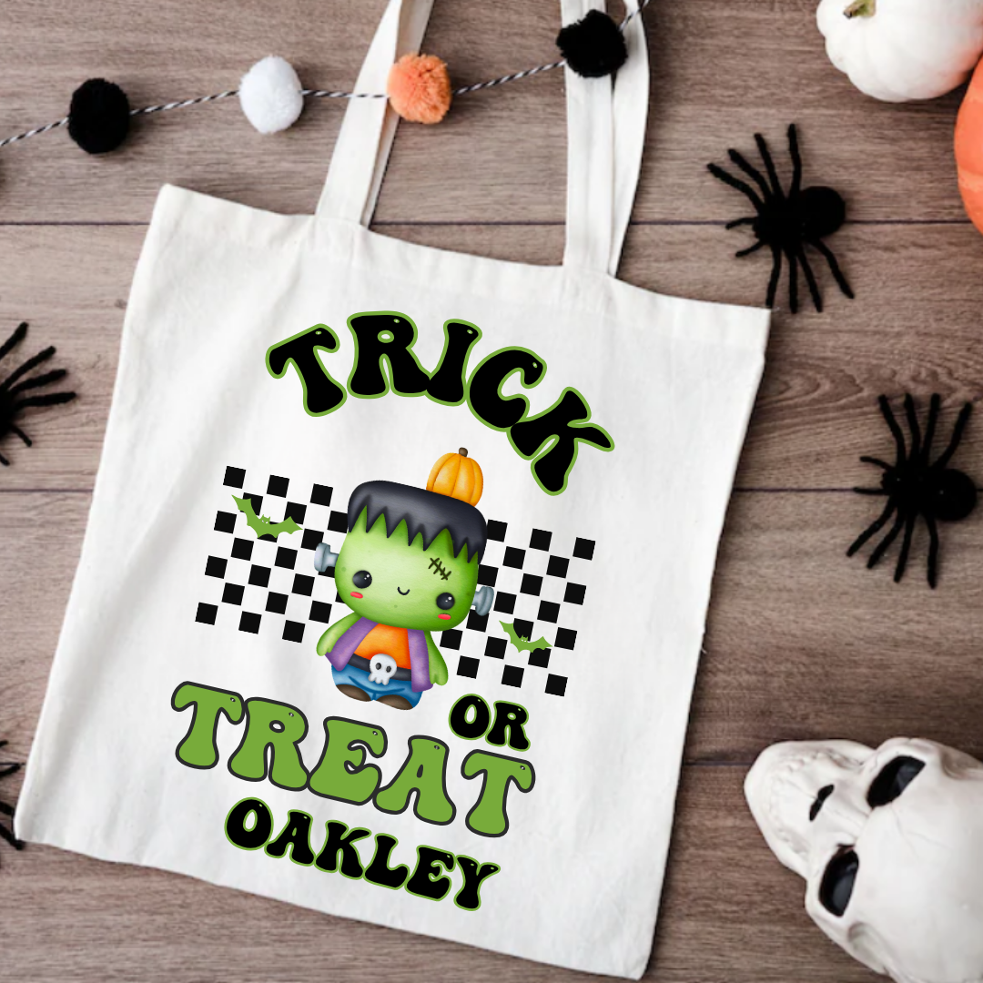 White tote bag with Halloween design featuring a character and text on a wooden surface.