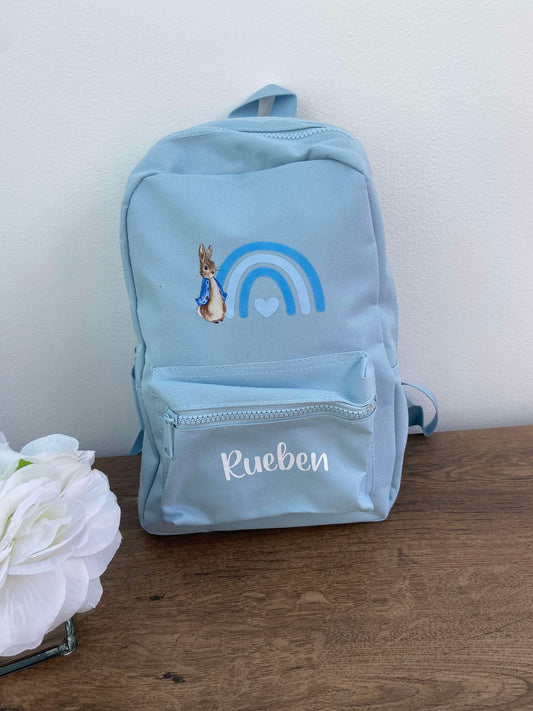 Light blue back pack featuring peter rabbit designs and the name rueben