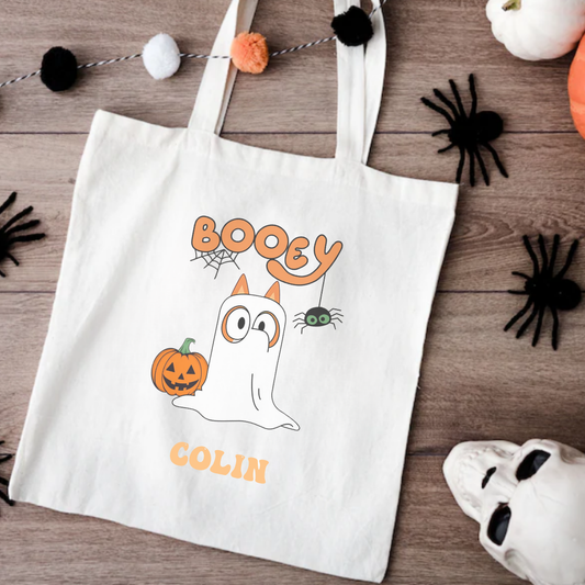 Halloween-themed tote bag with ghost and pumpkin design on a wooden surface.