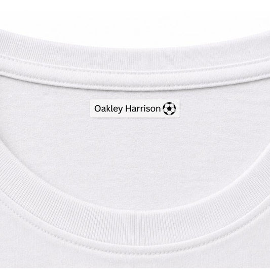 Close-up of a white crew-neck t-shirt showing the inner neck label with the text 'Oakley Harrison' and a small soccer ball logo.