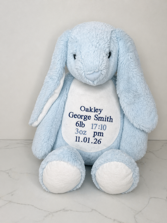 Blue plush bunny toy with embroidered baby details on a light gray background