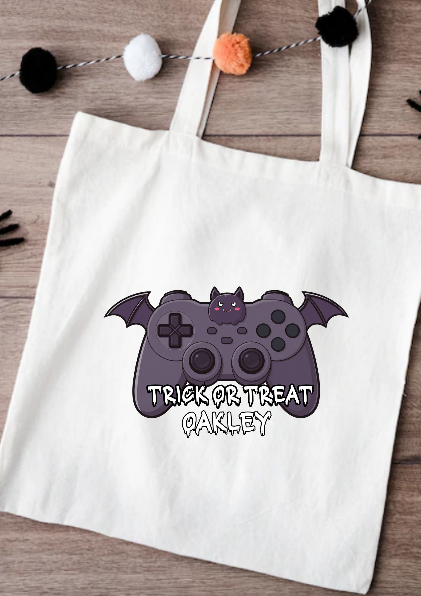 Tote bag with Halloween-themed design featuring a bat and game controller, on a wooden surface.