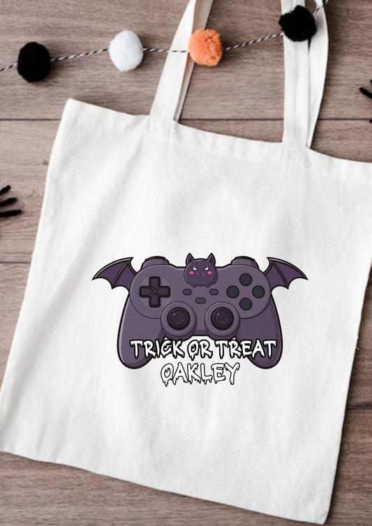 Tote bag with Halloween-themed design featuring a bat and game controller, on a wooden surface.