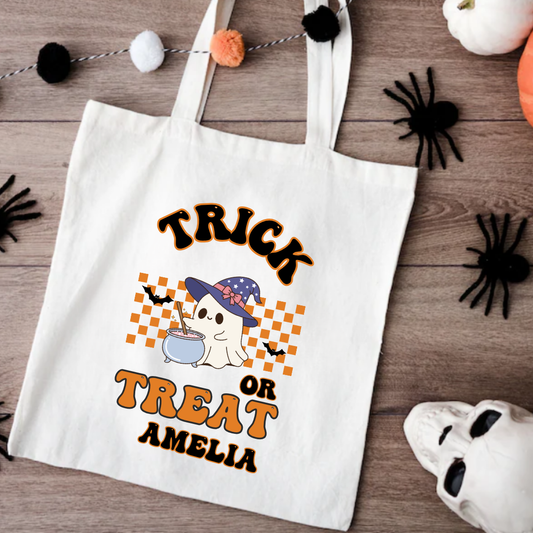 Halloween-themed tote bag with ghost and potion design on a wooden surface with Halloween decorations.