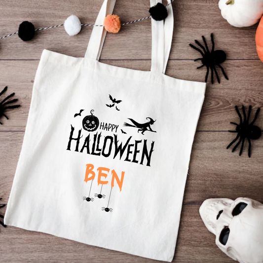 White tote bag with Halloween-themed design on a wooden surface with decorative items.