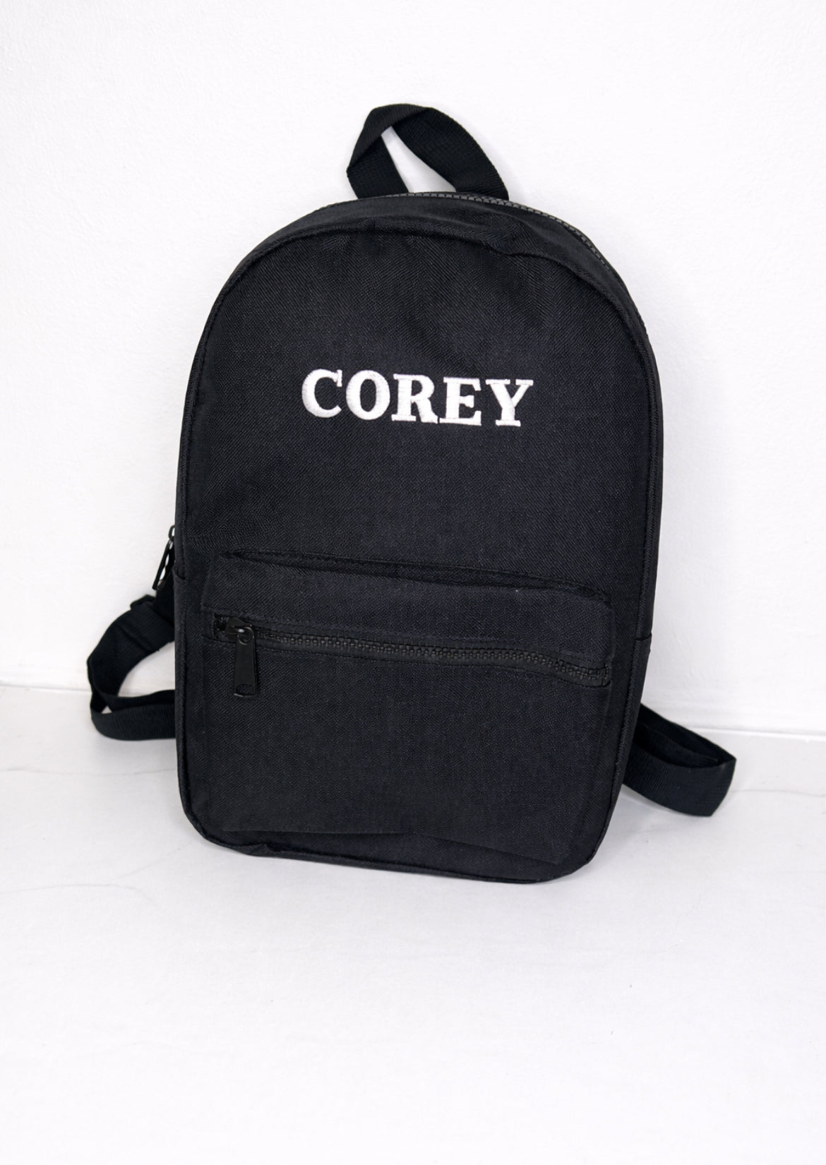 Black backpack with 'COREY' text on a white background