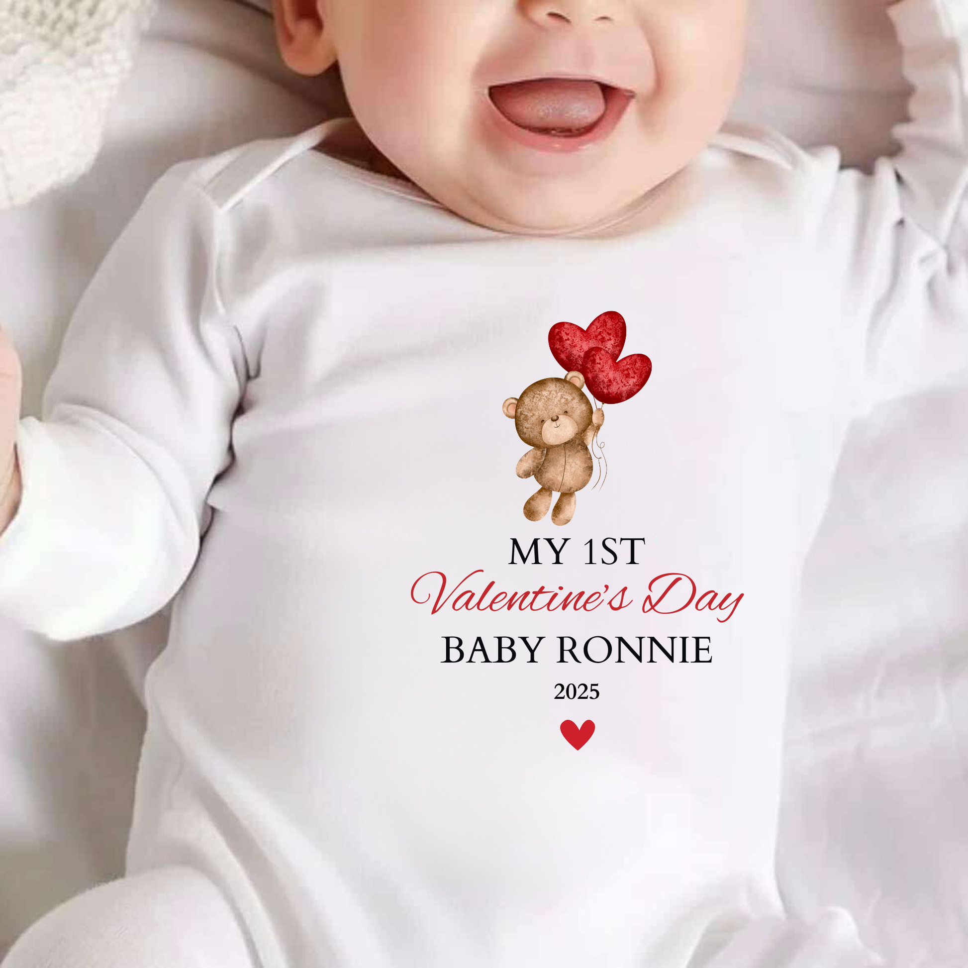 Baby wearing a white onesie with a Valentine's Day design and text.
