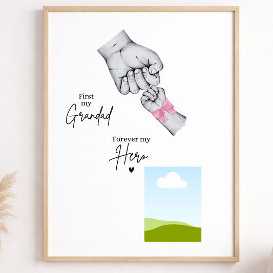 Framed artwork with two hands holding each other, text 'First my Grandad Forever my Hero', and a small landscape illustration on a wall.