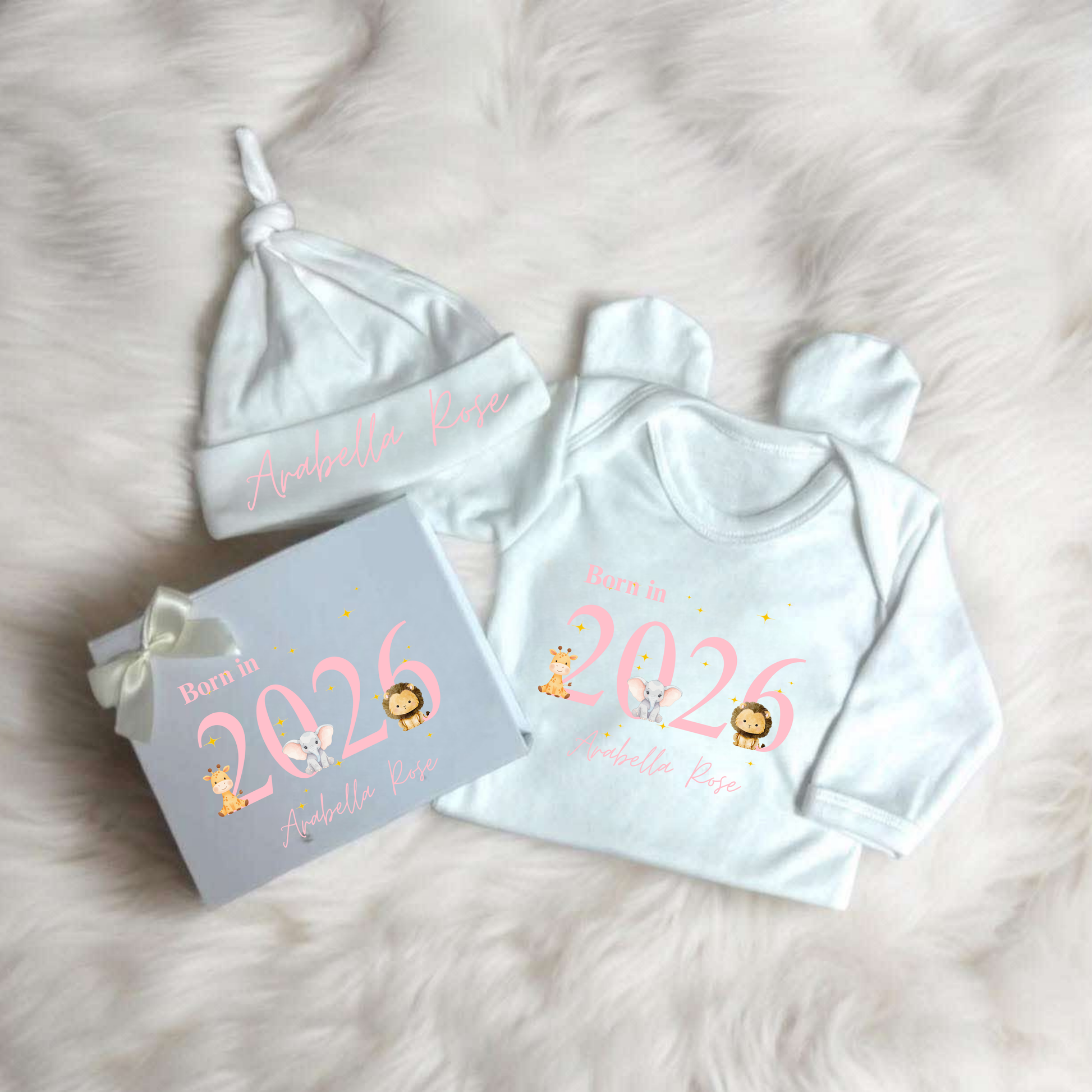 Baby outfit set with hat, onesie, and box on a soft surface