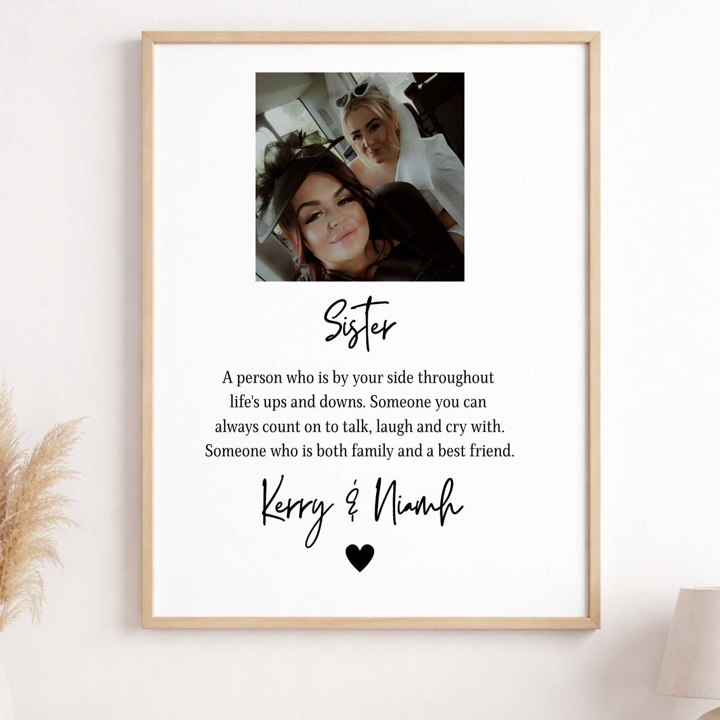 Framed print with a photo of two people and text about a sister on a wall.
