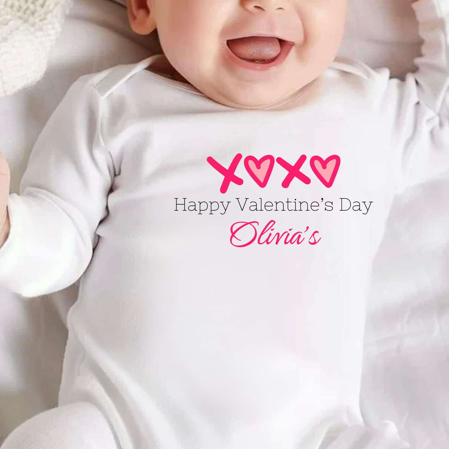 Baby wearing a white onesie with Valentine's Day text and hearts.