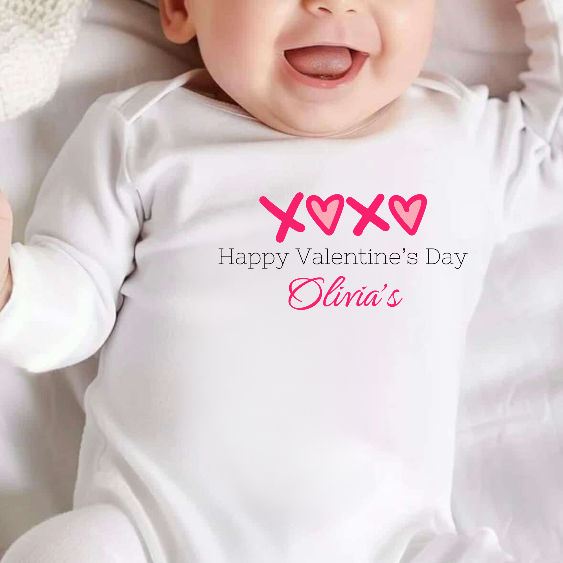 Baby wearing a white onesie with Valentine's Day text and hearts.