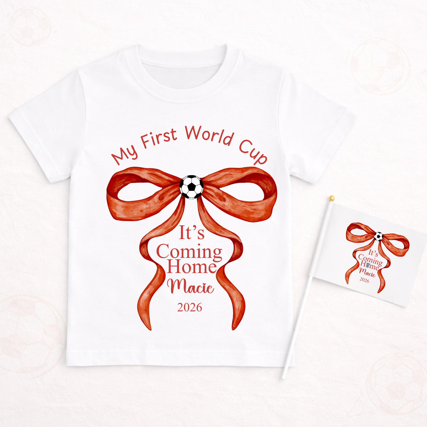 White t-shirt with red bow graphic and text 'My First World Cup It's Coming Home Macie 2026' on a white background