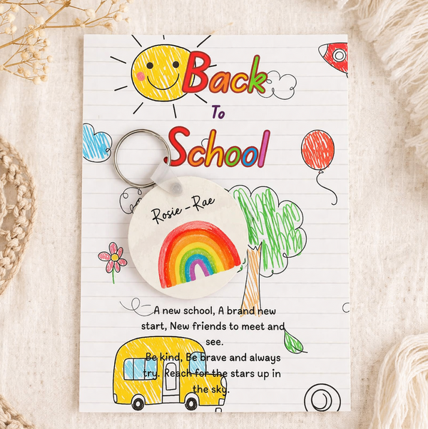 Keychain with 'Back to School' design featuring a rainbow, sun, and school bus on a white background.