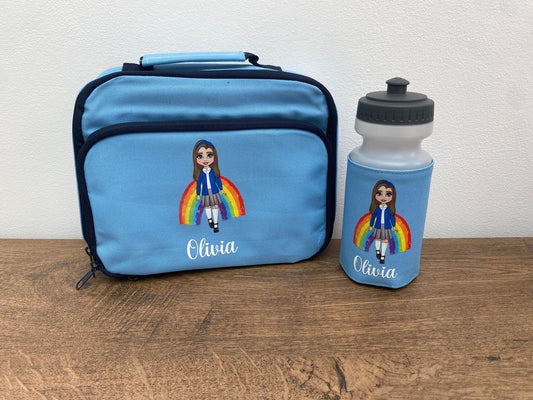 A personalized lunch bag and bottle set for kids, with the name 'Olivia' on them. The bag is blue with a picture of a girl wearing a rainbow-themed outfit, and there's a white bottle with a blue cap, also featuring the name 'Olivia'.