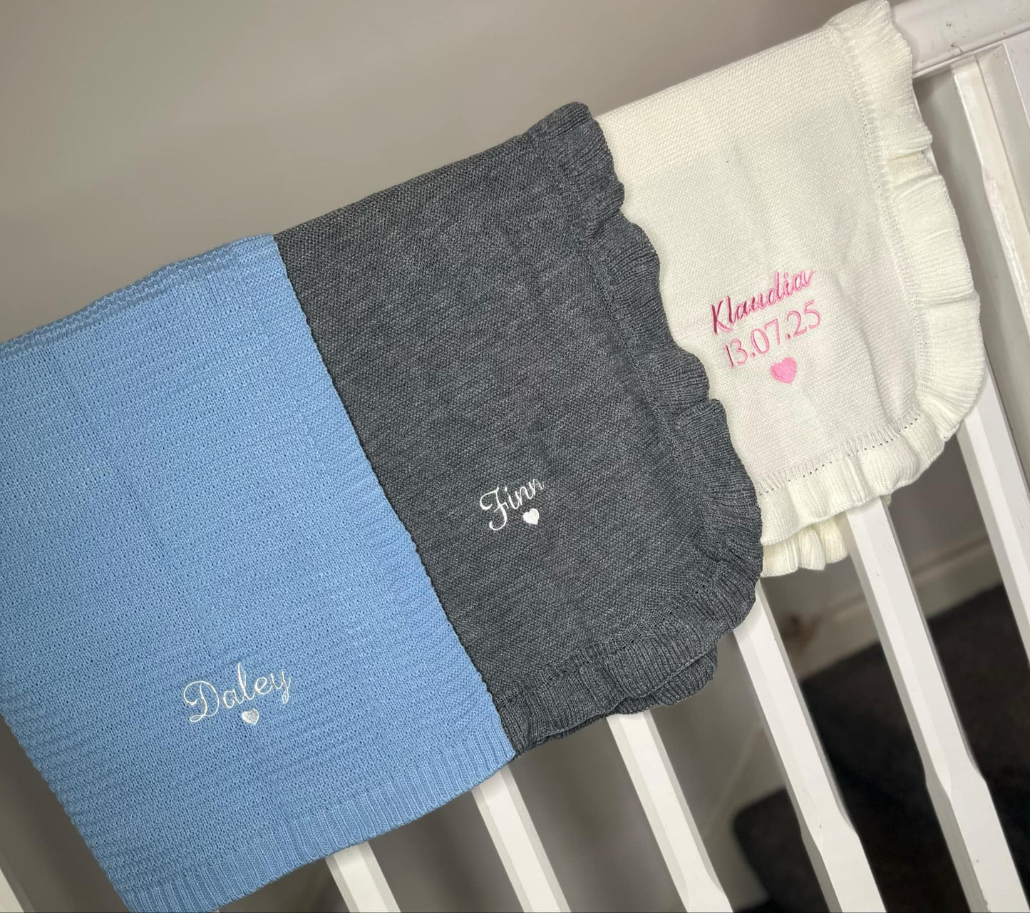 Baby blankets with embroidered names on a crib