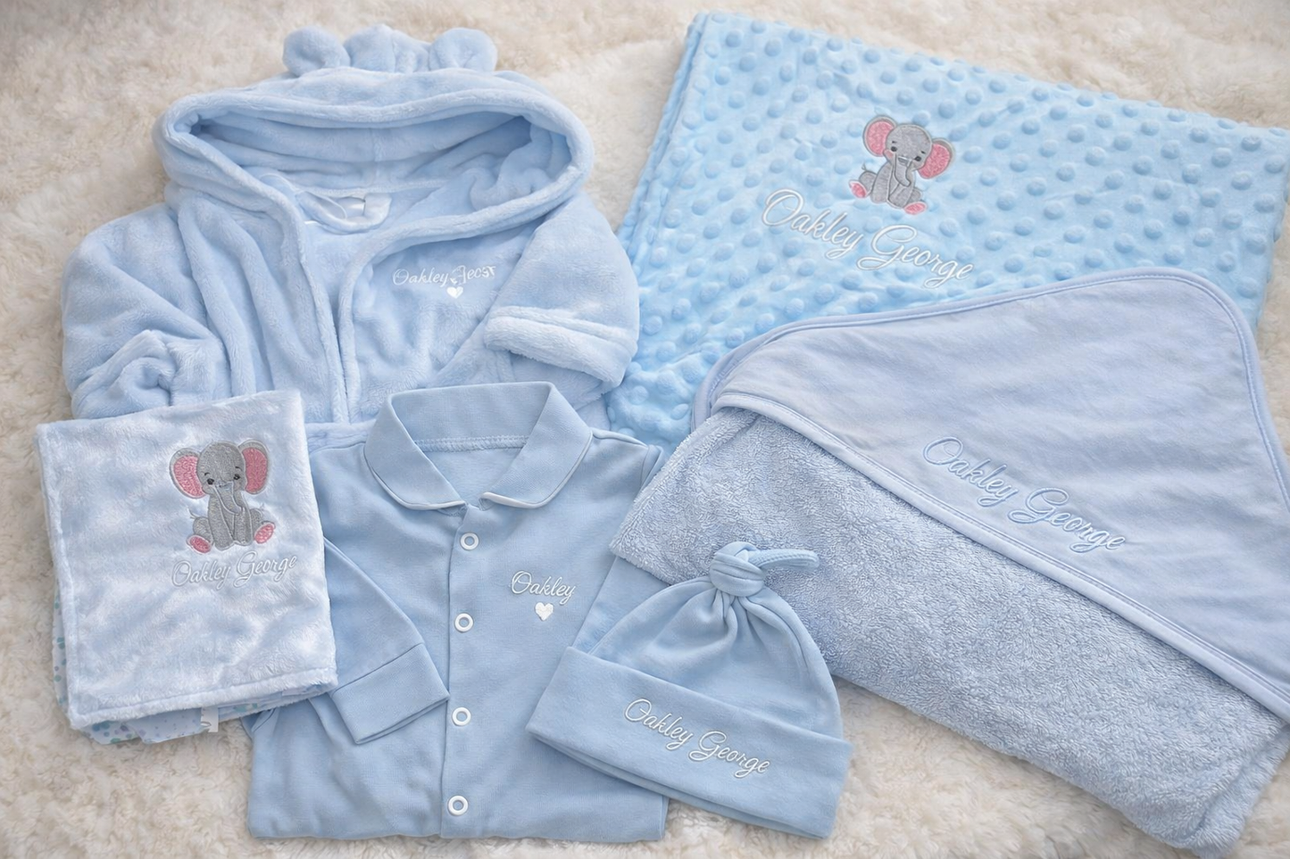 Baby clothing set with blue robe, shirt, and hats on a beige surface.