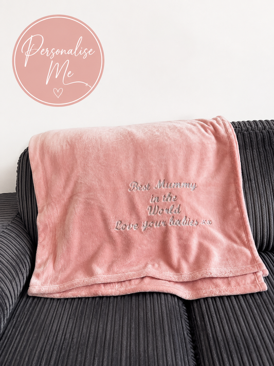 Personalised pink embroidered fleece blanket with custom text displayed on soft neutral background