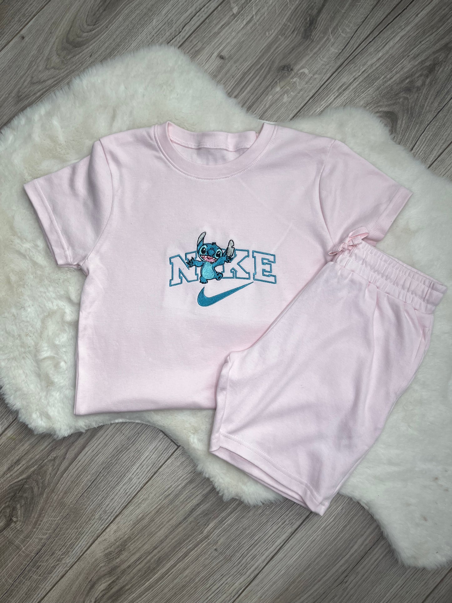 Personalised pink kids short set with embroidered character inspired design on matching t-shirt and shorts flat lay on white rug